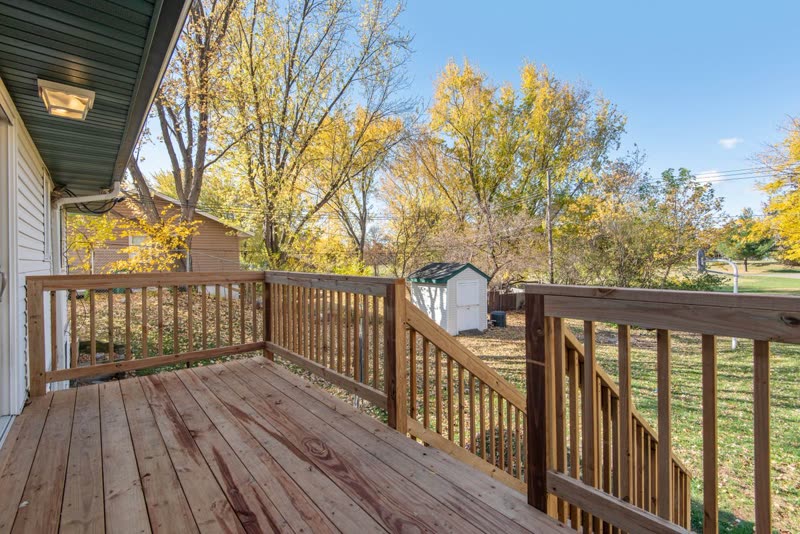 Wood deck with railings and stairs down to a back yard